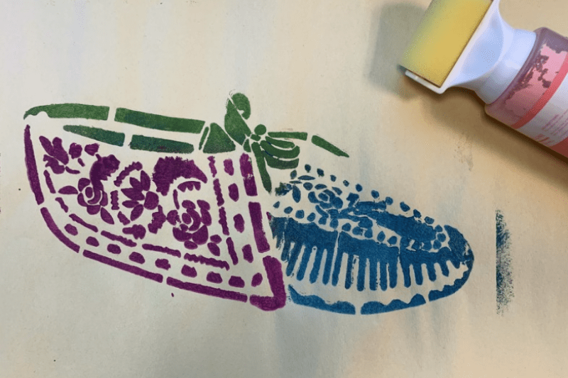 A moccasin is stencilled in purple, green, and blue.