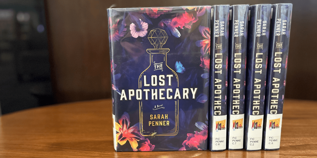 Copies of The Lost Apothecary by Sarah Penner lined up on a coffee table.