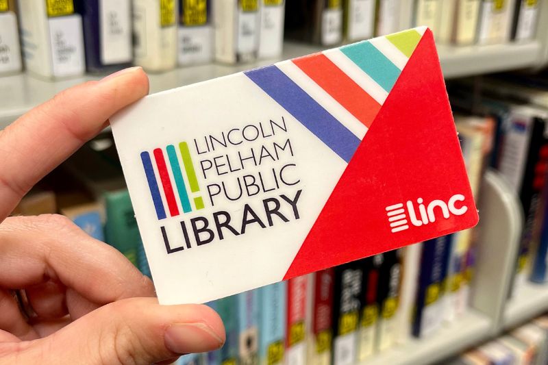 Hand holding library card in front of books