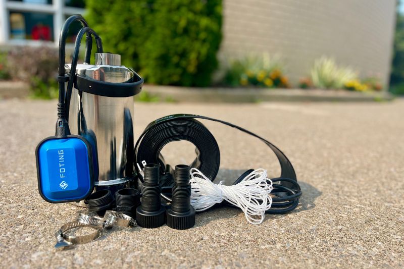 A stainless steel submersible pump, house, and accessories sitting on the sidewalk.